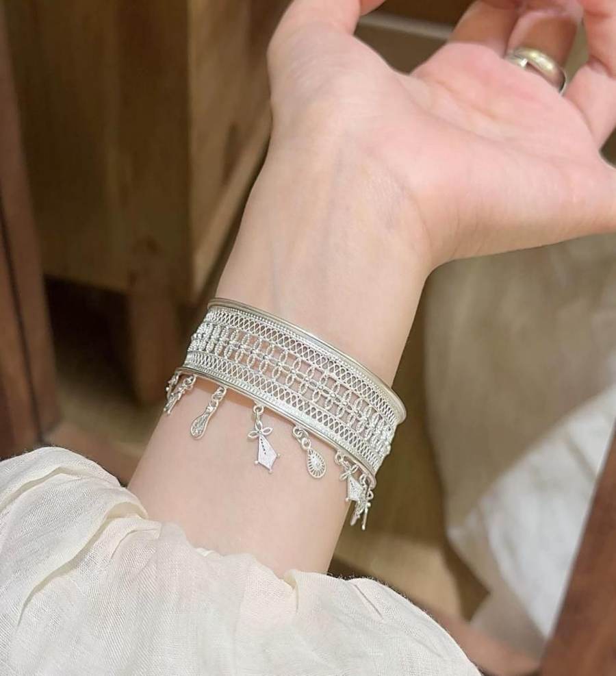 Silver cuff bracelet with hanging tassels worn on a wrist