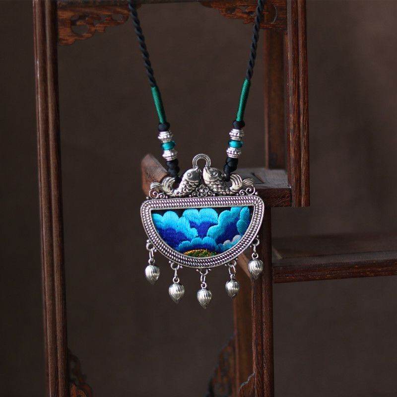 Silver pendant with a blue floral centre and a blue tassel