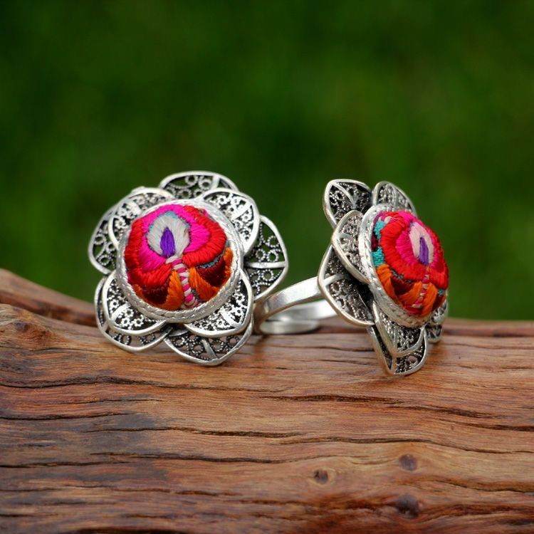 Two silver rings with red flower centres on a branch