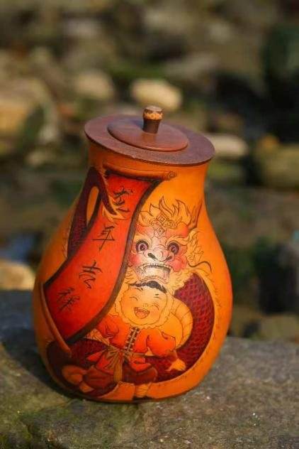 An orange lidded gourd jar decorated with a dragon and a smiling figure