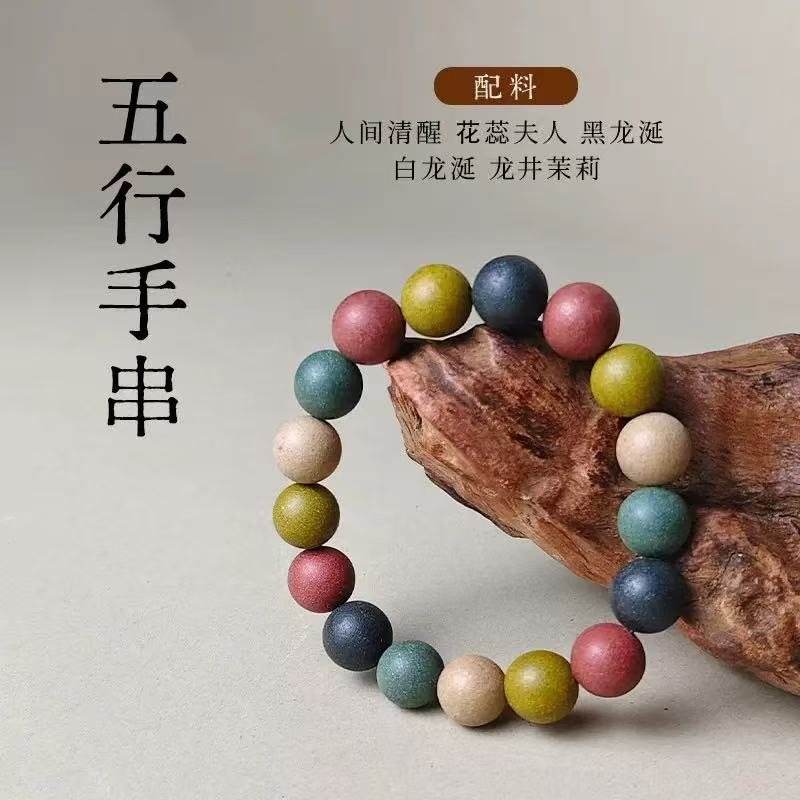 A bracelet of multi-coloured beads resting on a piece of root wood, with an ingredient card