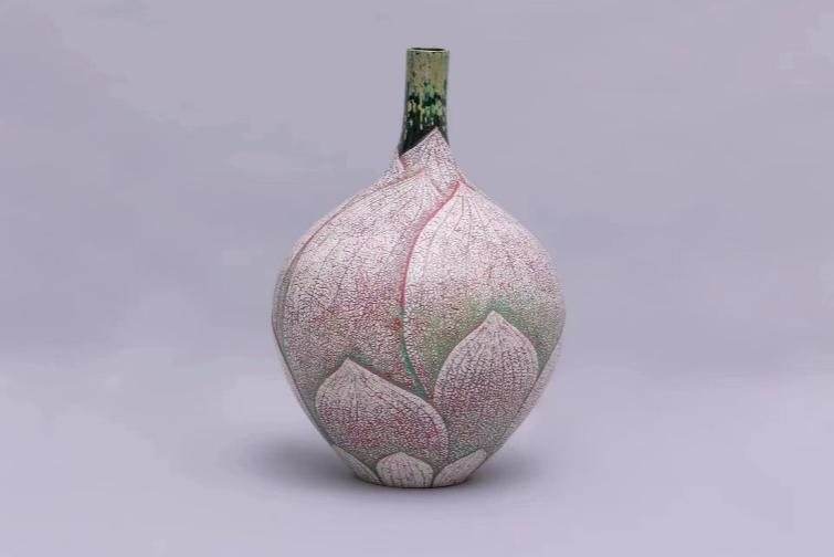A pale pink vase shaped like a lotus bud on a lilac background