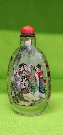 A glass snuff bottle with a red stopper, painted inside with a group of figures