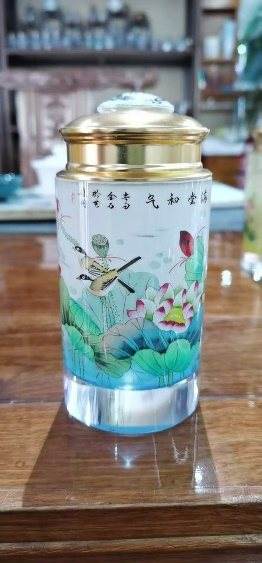 A glass jar with a gold lid, painted with a lotus scene and calligraphy