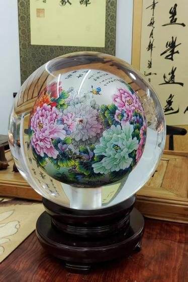 A crystal sphere on a dark stand, painted inside with peonies